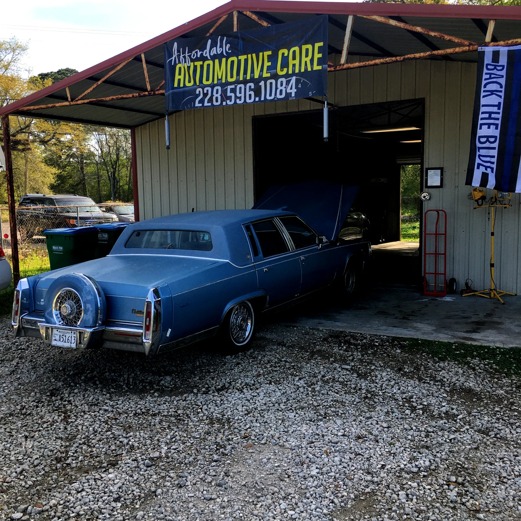 A blue classic Cadillac parked at our open bay, under the Affordable Automotive Care sign