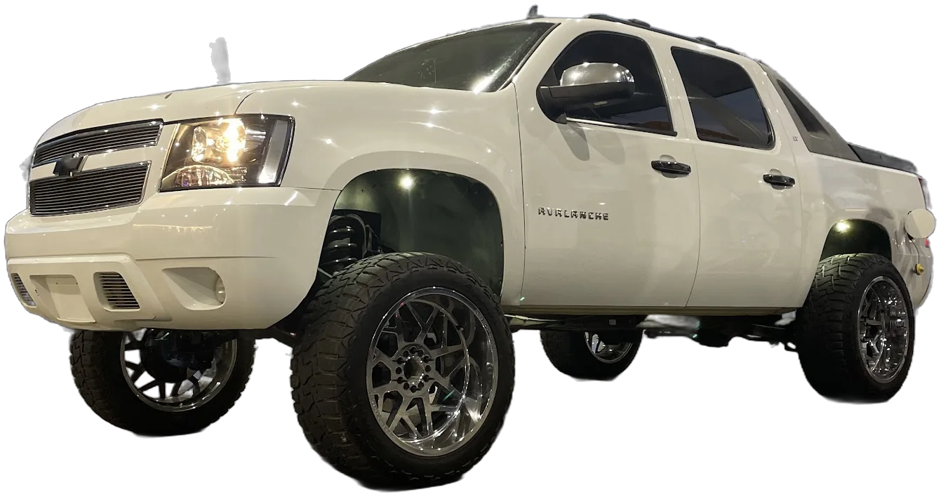A white lifted Chevy Avalanche on dark mesh wheels