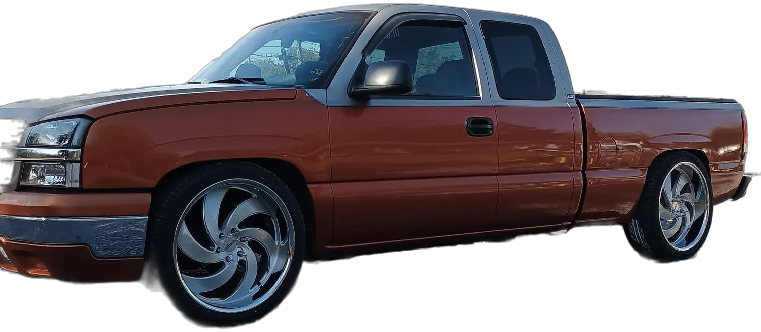 A two-tone orange Chevy pickup, lowered, on polished spinner wheels