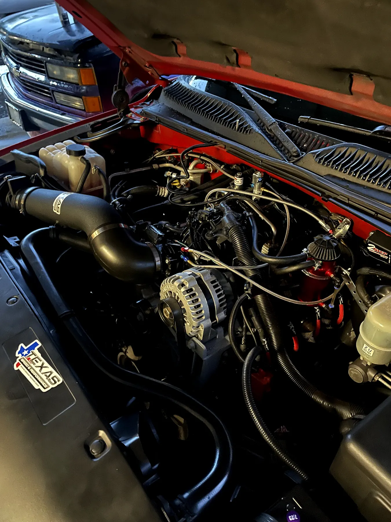 The engine bay of a red Chevy truck, open on our lot