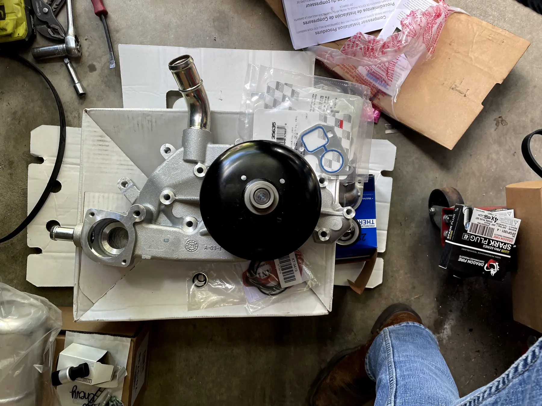 A new water pump on its box on our shop floor, with its gaskets laid out beside it